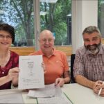 Gruppenfoto der Unterzeichnenden, Pfarrerin Schröder hält den unterschriebenen Vertag in die Kamera.