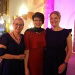 Die drei Organisatorinnen des Balls vor dem stimmungsvoll beleuchteten Chorraum der Marienkirche Hanau.