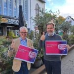 stv. Dekan Daniel Geiss und Dekan Martin Lückhoff halten jeweils ein Plakat der Kampagne "Zeichen setzen" in der Hand und einen Daumen nach oben.