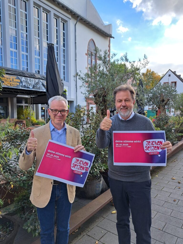 stv. Dekan Daniel Geiss und Dekan Martin Lückhoff halten jeweils ein Plakat der Kampagne "Zeichen setzen" in der Hand und einen Daumen nach oben.