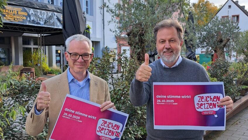 stv. Dekan Daniel Geiss und Dekan Martin Lückhoff halten jeweils ein Plakat der Kampagne "Zeichen setzen" in der Hand und einen Daumen nach oben.