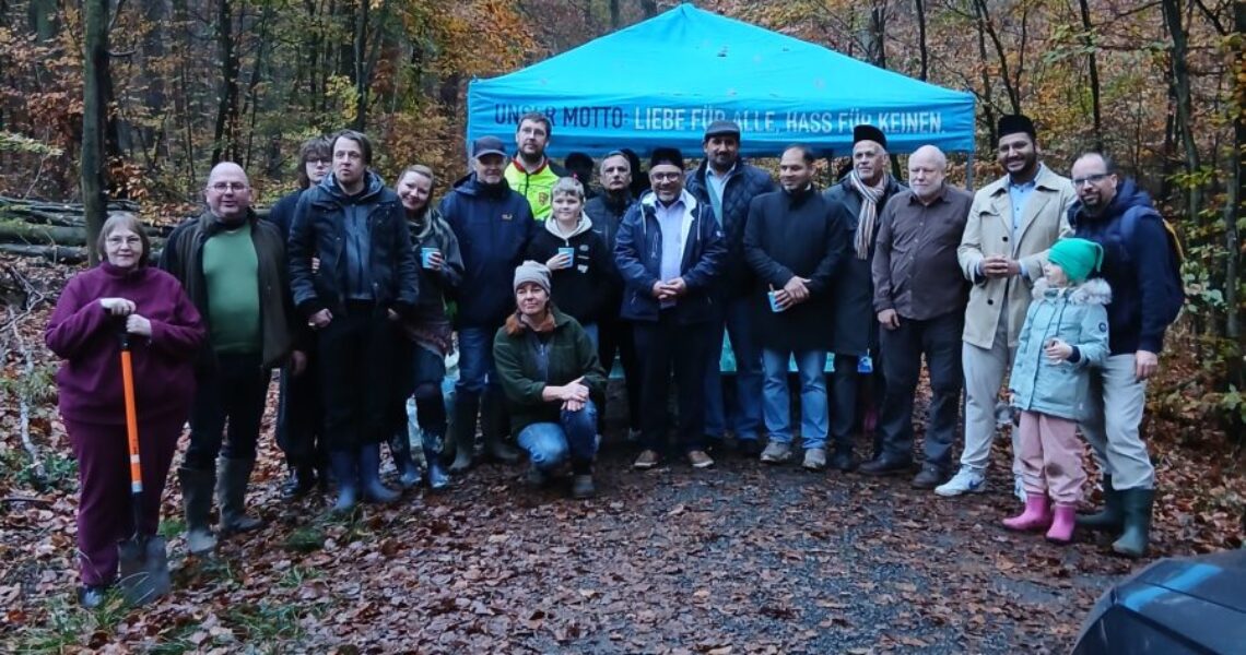 Gruppenfoto der Teilnehmenden der Baumpflanzaktion im Wald vor einem blauen Pavillon.
