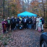 Gruppenfoto der Teilnehmenden der Baumpflanzaktion im Wald vor einem blauen Pavillon.