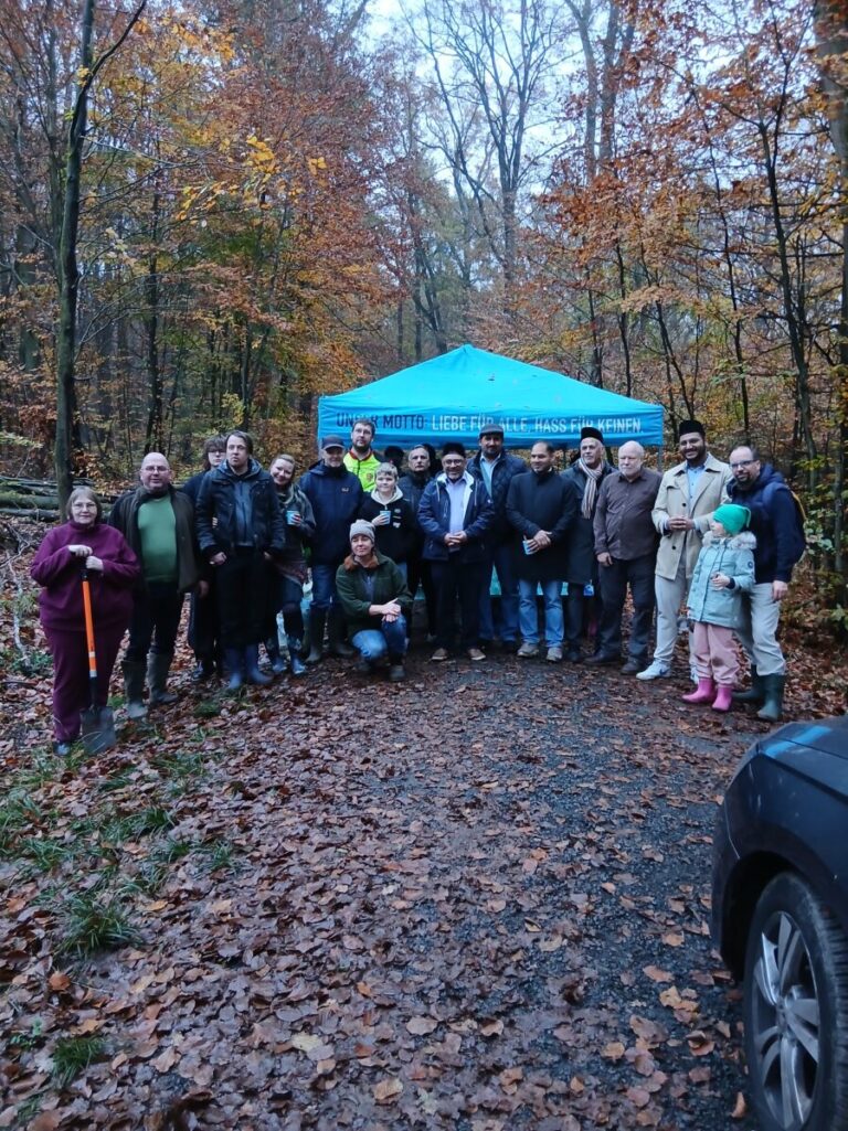 Gruppenfoto der Teilnehmenden der Baumpflanzaktion im Wald vor einem blauen Pavillon.