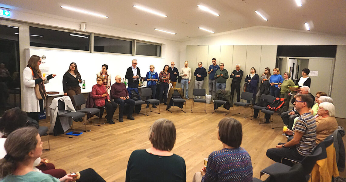 Personen stehen und sitzen in einem Kreis, die Vorsitzende des KV spricht zu den Anwesenden