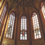 Bild vom Chorraum mit den historischen Glasmalereien durch die Sonnenlicht scheint