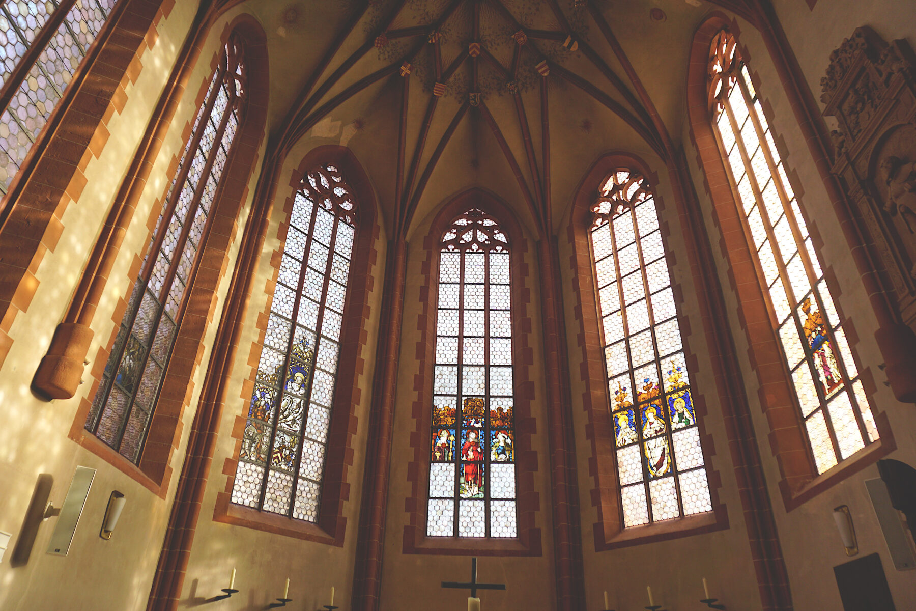 Bild vom Chorraum mit den historischen Glasmalereien durch die Sonnenlicht scheint