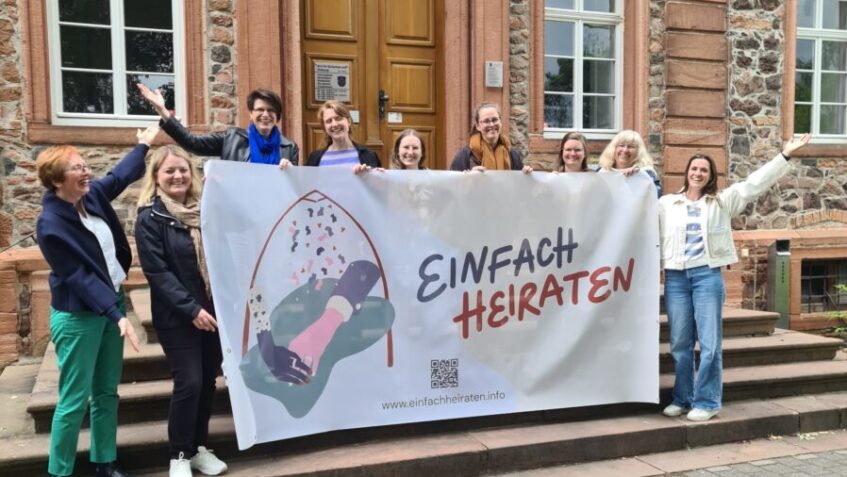 Pfarrpersonen aus dem Kirchenkreis Hanau mit dem großen Banner zur Aktion Einfach Heiraten vor dem Schloss Langenselbold